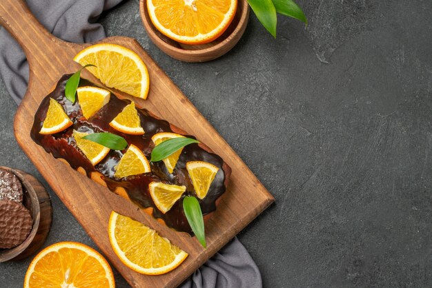 Horizontal view of soft tasty cakes cut oranges with biscuits on wooden cutting board and towel