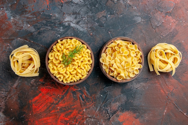 Horizontal view of various types of uncooked pastas on mixed color table