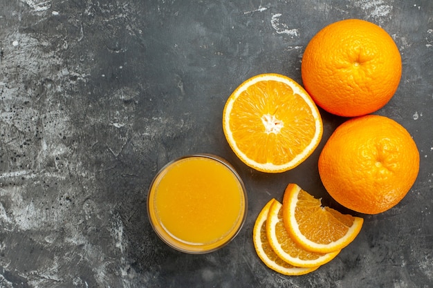 Horizontal view of vitamin source cut chopped and whole fresh oranges and juice on gray background