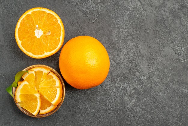 Horizontal view of whole and chopped fresh lemons on dark table