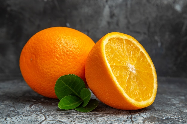 Horizontal view of whole and cut in half fresh oranges on gray background