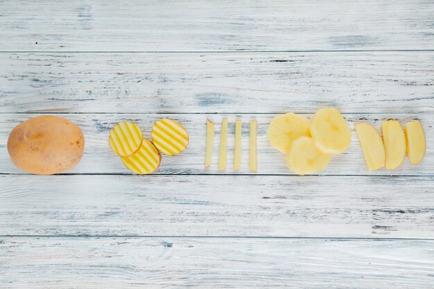 Horizontal view of whole and sliced potato on wooden background with copy space