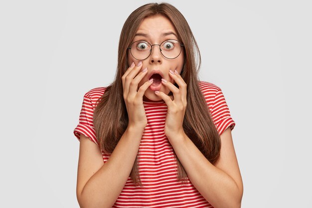 目がバグのある恐怖の白人女性、驚きから顎を落とし、手を口の近くに保つ