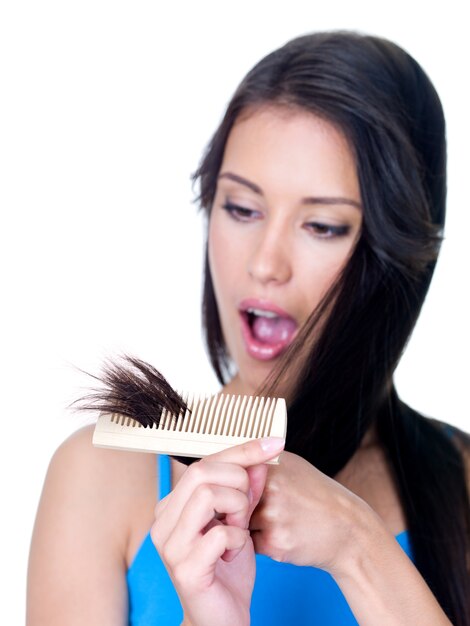 Horror on the face of young woman looking at the unhealthy ends of hair - isolated