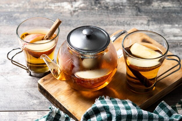 Hot apple drink with spices on wooden table