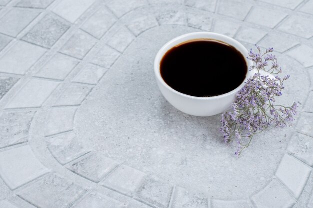 Hot, aroma tea with flowers on white surface.