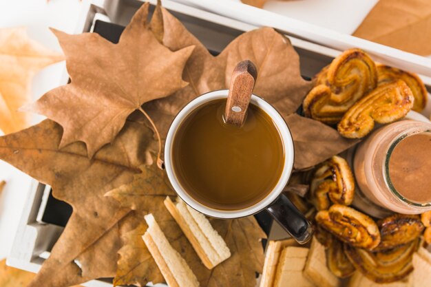 Hot beverage on leaves near pastry