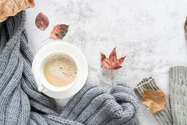 Hot beverage with warm sweater on light surface