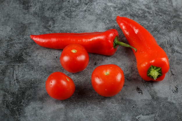 Free photo hot chili peppers with tomatoes on a stone table.