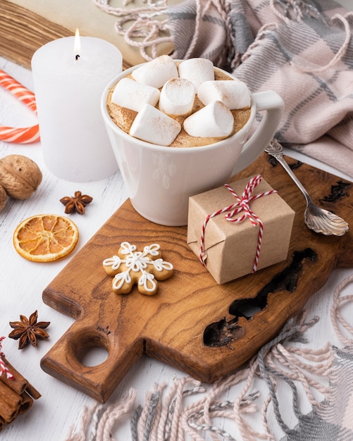 Hot cocoa with marshmallows in cup with present and candle