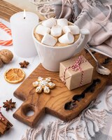 hot cocoa with marshmallows in cup with present and candle