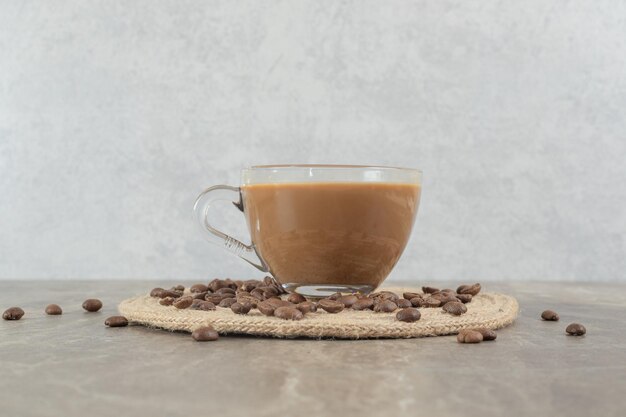 Горячий кофе и кофейные зерна на мраморном столе