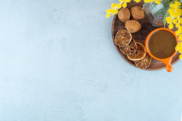 Hot coffee, orange slices and sweet cookies on wooden plate.