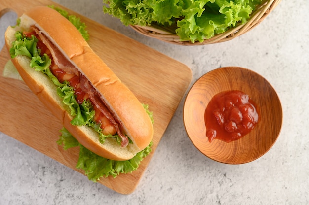 木製まな板の上のレタスとトマトソースのホットドッグ