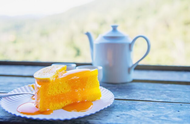 熱い食べるカップと緑の自然の背景を持つオレンジケーキ