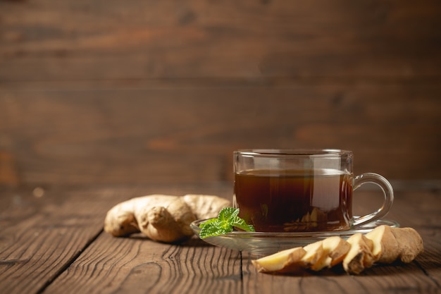 Hot ginger juice and ginger sliced on wooden table.