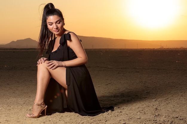 일몰에 땅과 사막에 앉아있는 뜨거운 소녀 고품질 사진