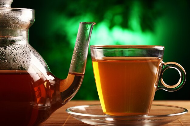 Hot green tea in glass teapot and cup