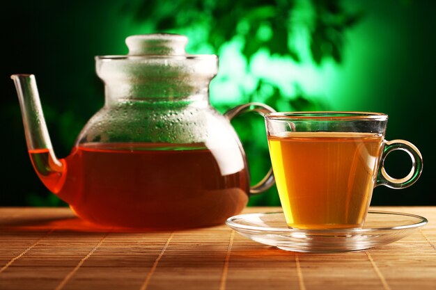 Hot green tea in glass teapot and cup