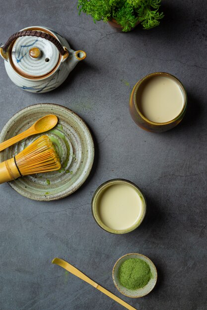 Hot green tea in a glass with cream topped with green tea, decorated with green tea powder.