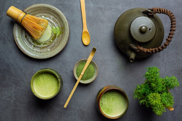 Hot green tea in a glass with cream topped with green tea, decorated with green tea powder.