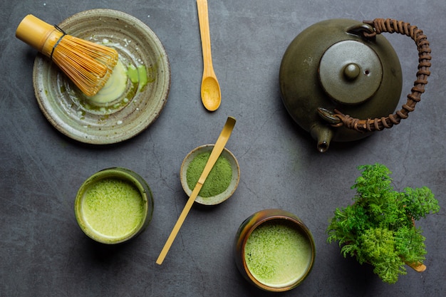 Hot green tea in a glass with cream topped with green tea, decorated with green tea powder.