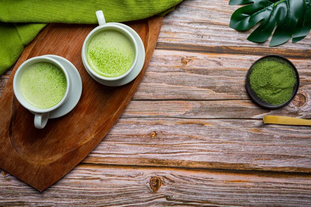 Hot green tea in a glass with cream topped with green tea, decorated with green tea powder.