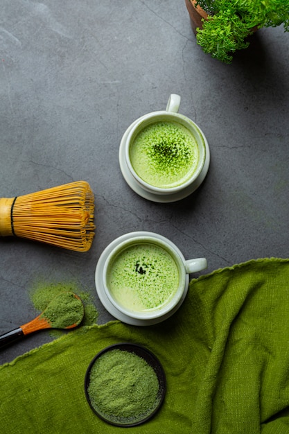 Free photo hot green tea in a glass with cream topped with green tea, decorated with green tea powder.