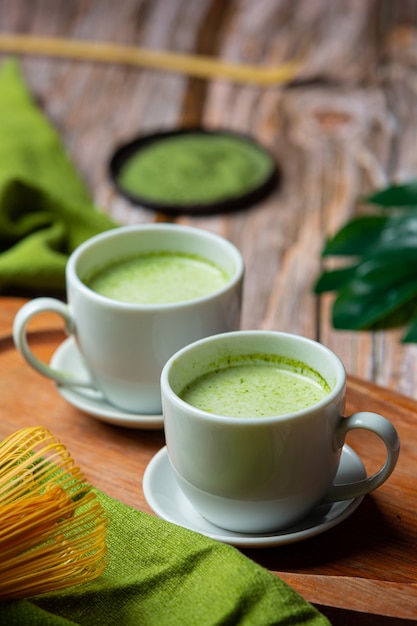 Бесплатное фото Горячий зеленый чай в стакане со сливками, увенчанный зеленым чаем, украшенный порошком зеленого чая.