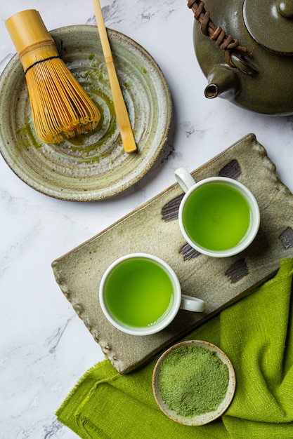 Бесплатное фото Горячий зеленый чай в стакане со сливками, увенчанный зеленым чаем, украшенный порошком зеленого чая.