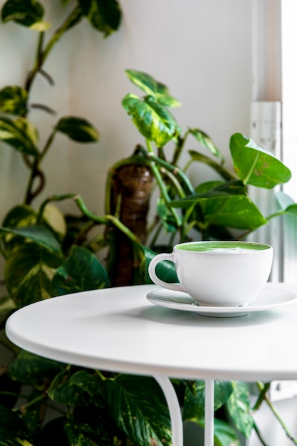 Hot green tea matcha latte in a cup on white table