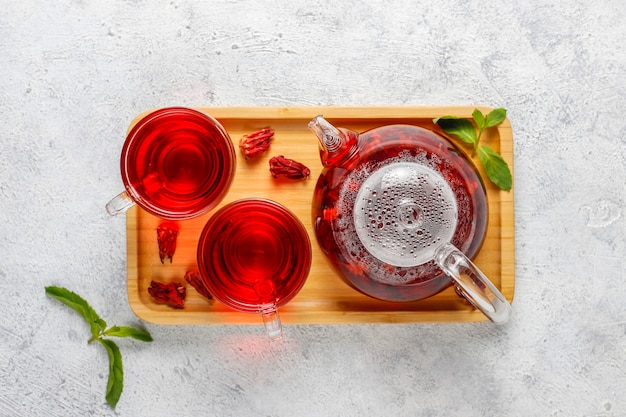 Hot hibiscus tea in a glass mug and glass teapot.