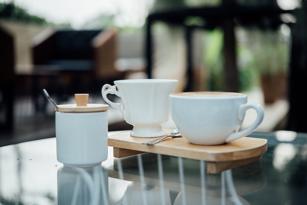 コーヒーショップの木のテーブルにコーヒーカップで熱いラテアート
