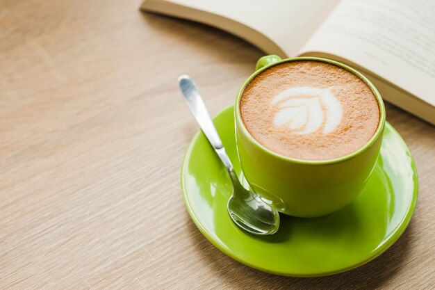 Hot latte coffee with latte art in green cup on table