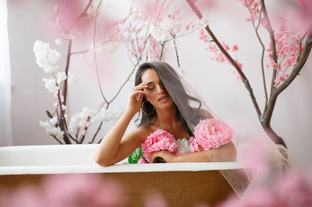 꽃 다발과 함께 욕조에 앉아 있는 뜨거운 모델 고품질 사진