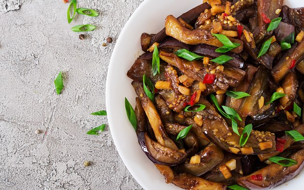 Hot spicy stew eggplant in Korean style with green onion. Aubergine saute. Vegan food. Flat lay. Top view