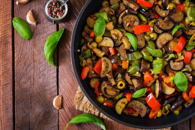 Foto gratuita spezzatino piccante speziato di melanzane, peperoni, olive e capperi con foglie di basilico. vista dall'alto