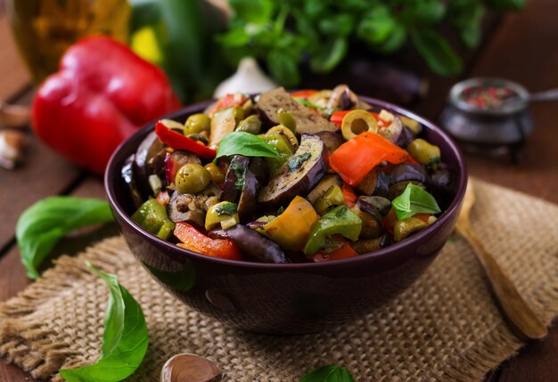 Hot spicy stew eggplant, sweet pepper, olives and capers with basil leaves.