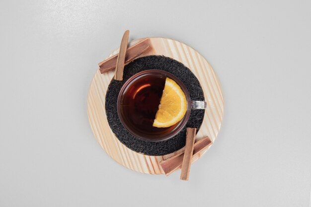 Hot tea with cinnamon and lemon on wooden plate.