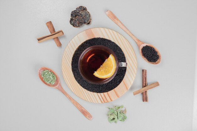 Hot tea with cinnamon and lemon on wooden plate.