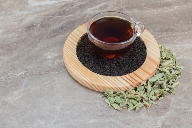 Горячий чай с сушеными листьями на деревянной тарелке.