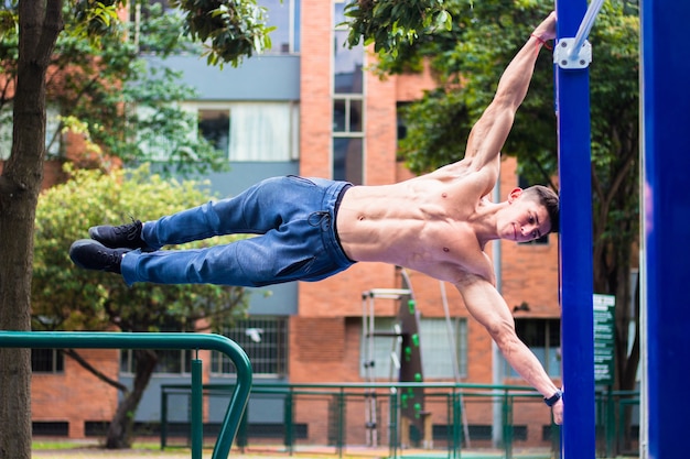 Foto gratuita giovane uomo muscoloso caldo che si allena su barre orizzontali