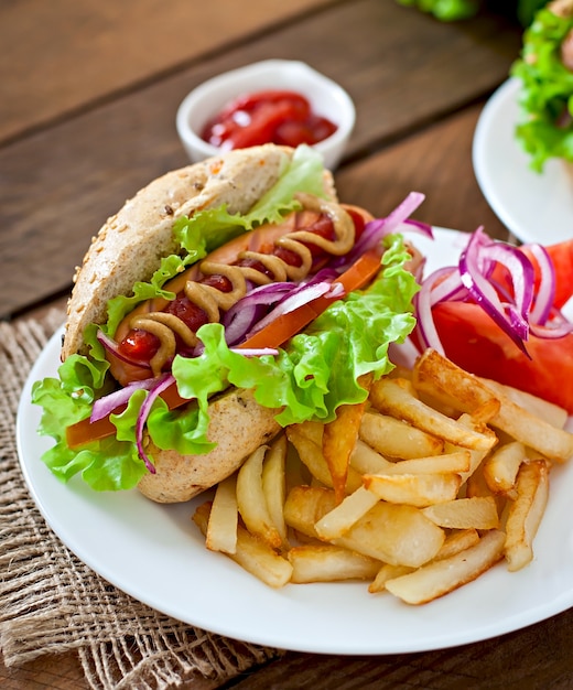 Hotdog with ketchup mustard and lettuce on wooden table.