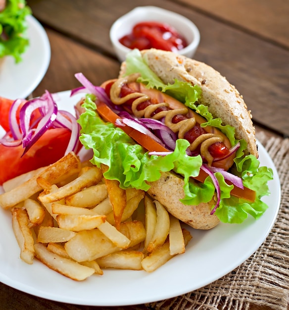 Hotdog with ketchup mustard and lettuce on wooden table.