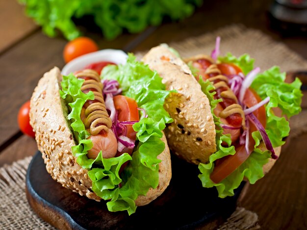 Hotdog with ketchup mustard and lettuce on wooden table.