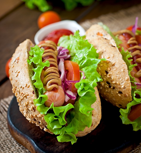 Hotdog with ketchup mustard and lettuce on wooden table.