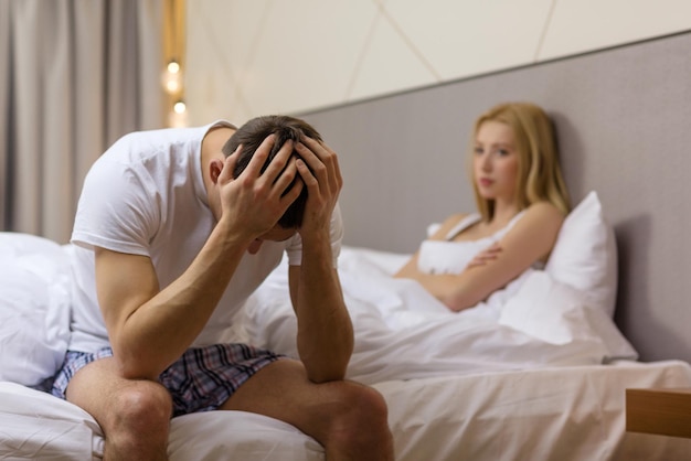 Отель, путешествия, отношения и концепция сексуальных проблем - расстроенный мужчина сидит на кровати с женщиной на спине