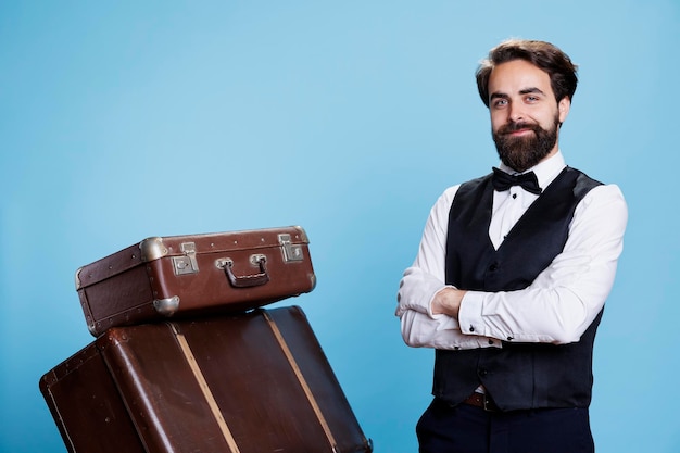 Free photo hotel worker with baggage pile on camera, providing luxury service to guests and helping with suitcases. professional bellhop or porter dressed in suit and tie feeling determined.