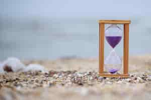 Free photo hourglass at the beach on the ground high quality photo