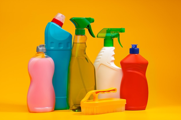 Бутылки с моющим средством для уборки дома на желтом фоне